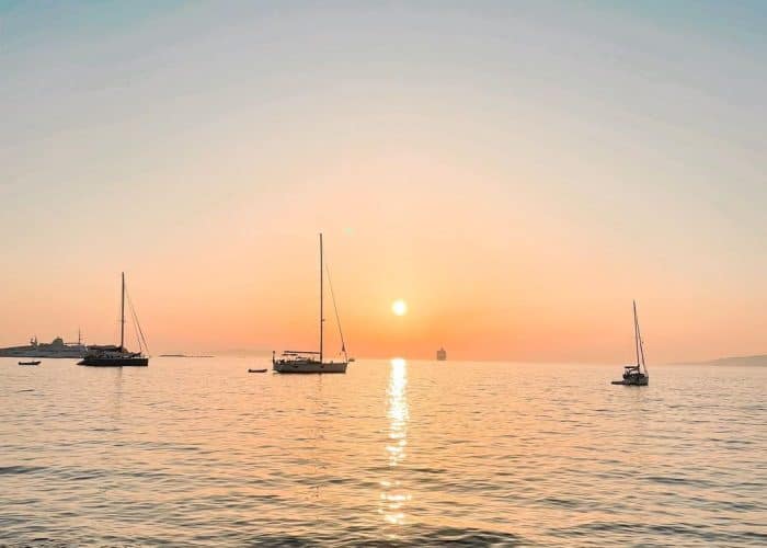 Mykonos sunset with sailboats greece pilgrimage tour