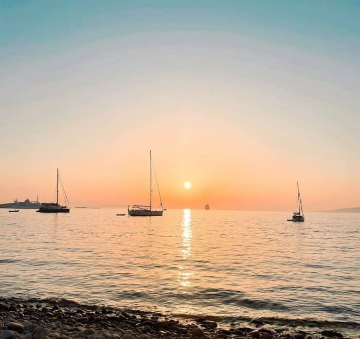 Mykonos sunset with sailboats greece pilgrimage tour