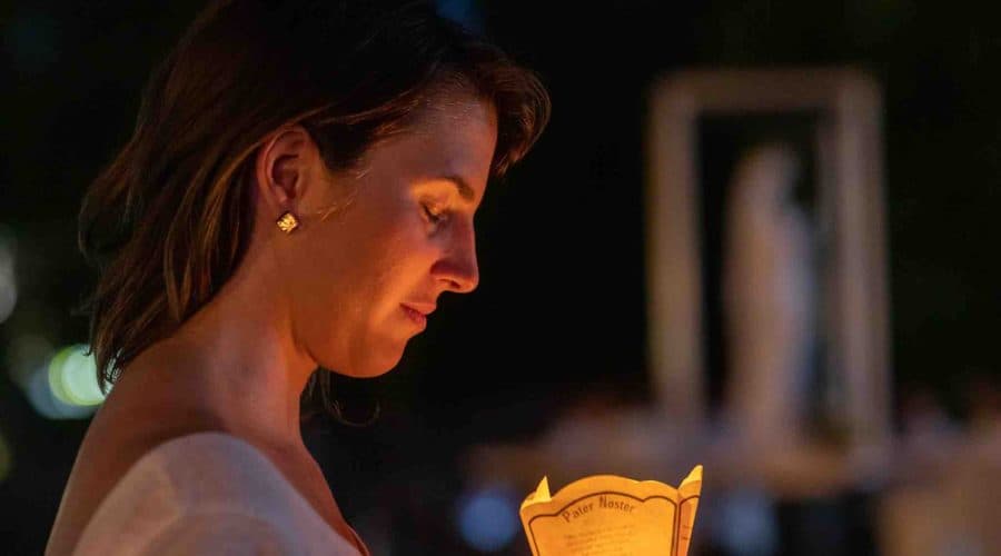 woman with candle at lourdes pilgrimage tour